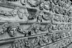 Sculpted faces and garlands adorn a stone wall.